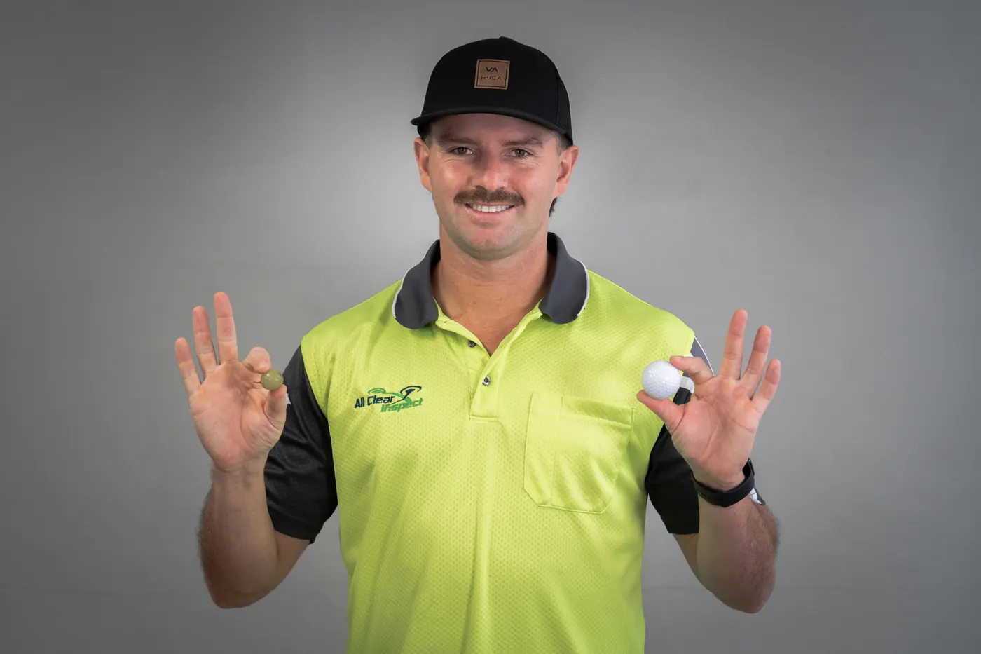 Inspector holding a golf ball and a grape to compare hailstone sizes