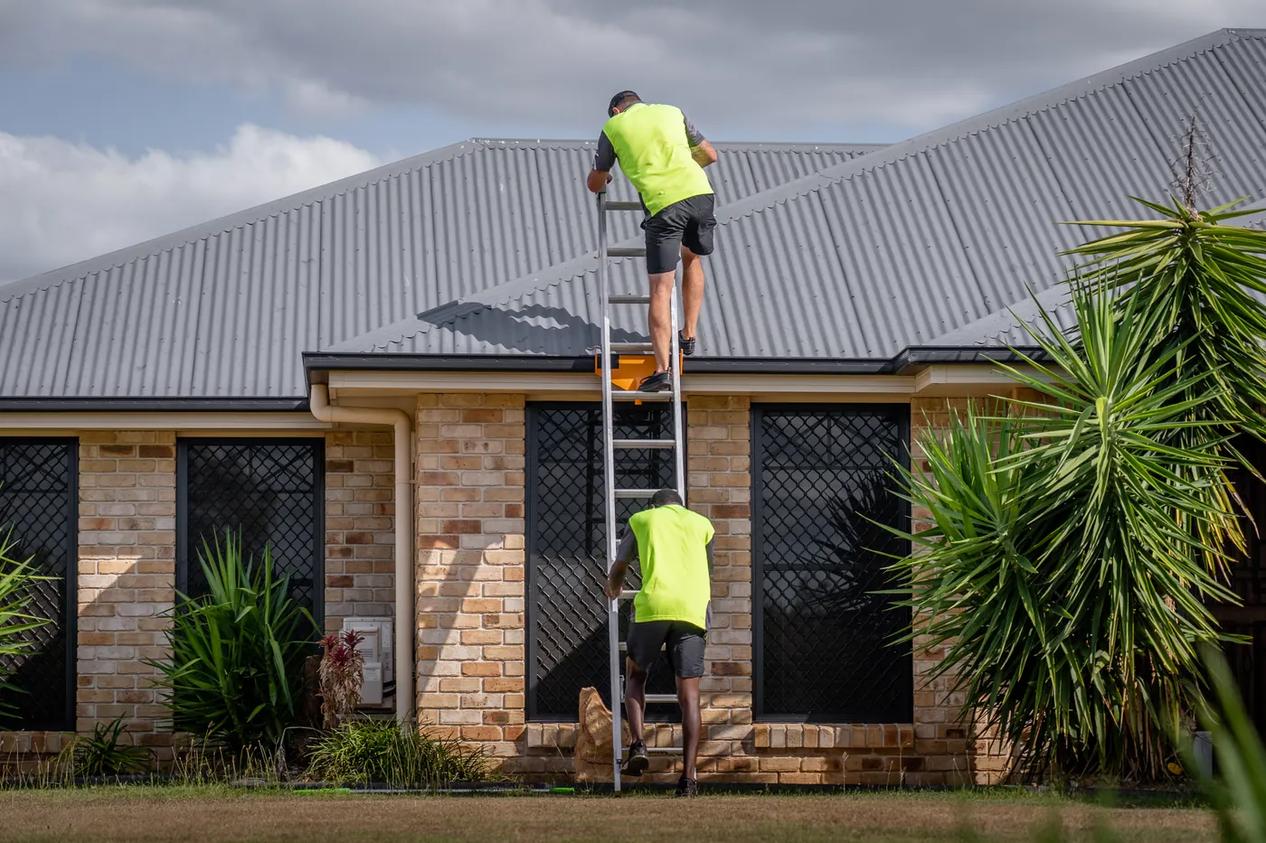 Two All Clear Inspect inspectors accessing a roof by ladder